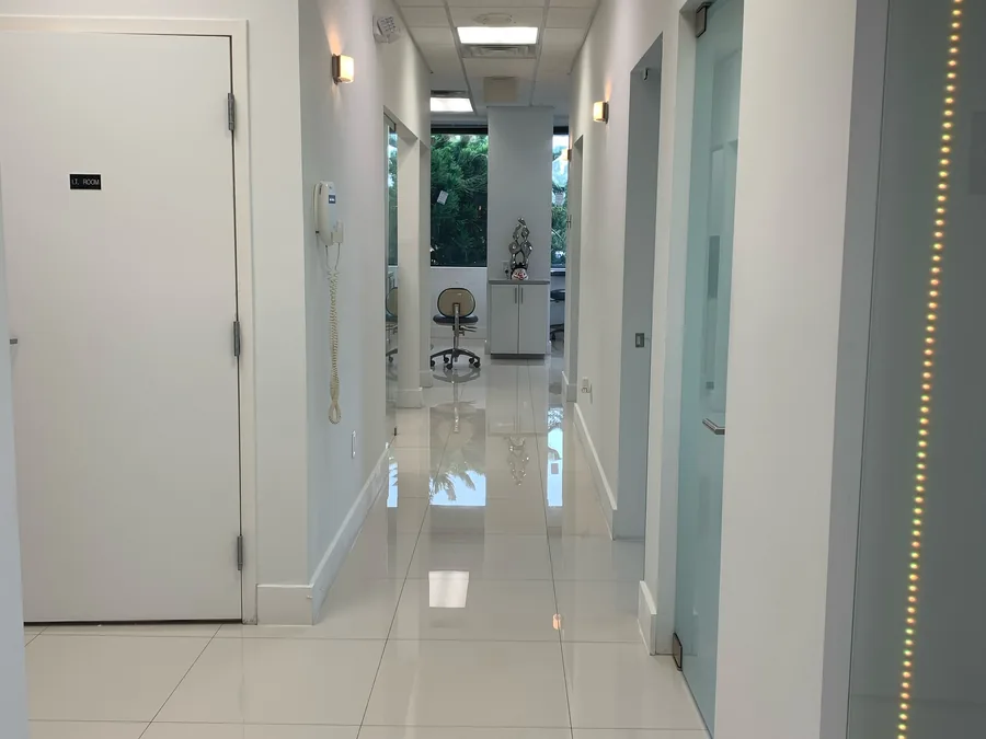 Un pasillo luminoso e impecable de la cl&iacute;nica, con paredes blancas, pisos pulidos y consultorios a lo largo